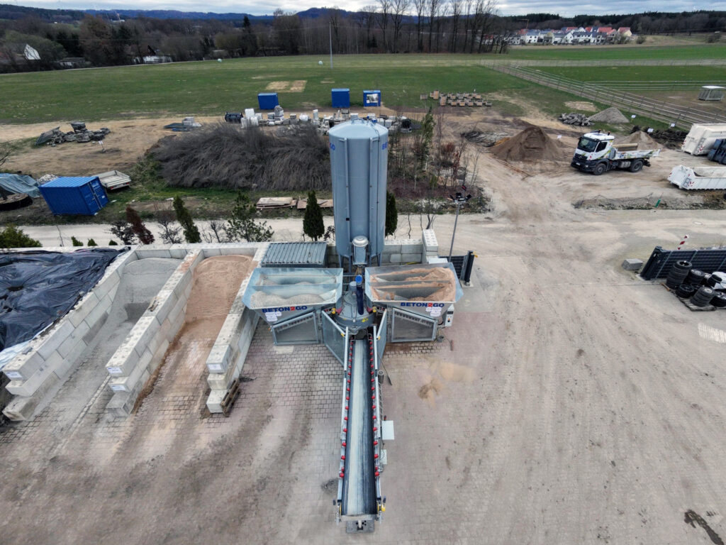 Luftbild der Betontankstelle Beton4U mit erkennbaren Material-Bunkern, Förderband und Silo.